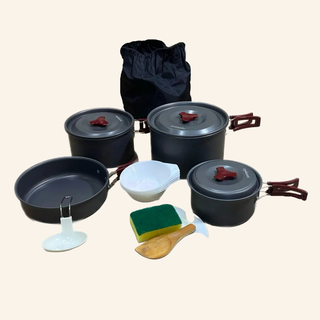 Set of camping cookware with pots, pans, and utensils on a white background